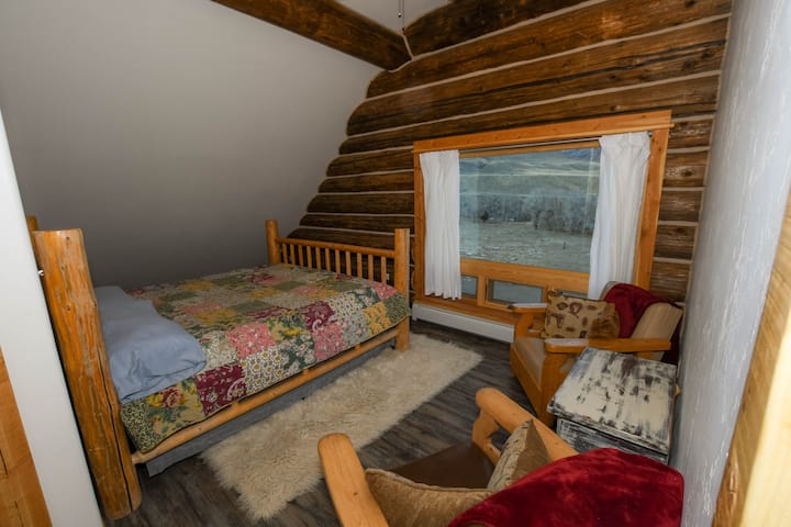 غرفة نوم بسرير بحجم كبير تقع في الطابق الثاني إطلالة رائعة على الجبل والنهر مع منطقة جلوس.  