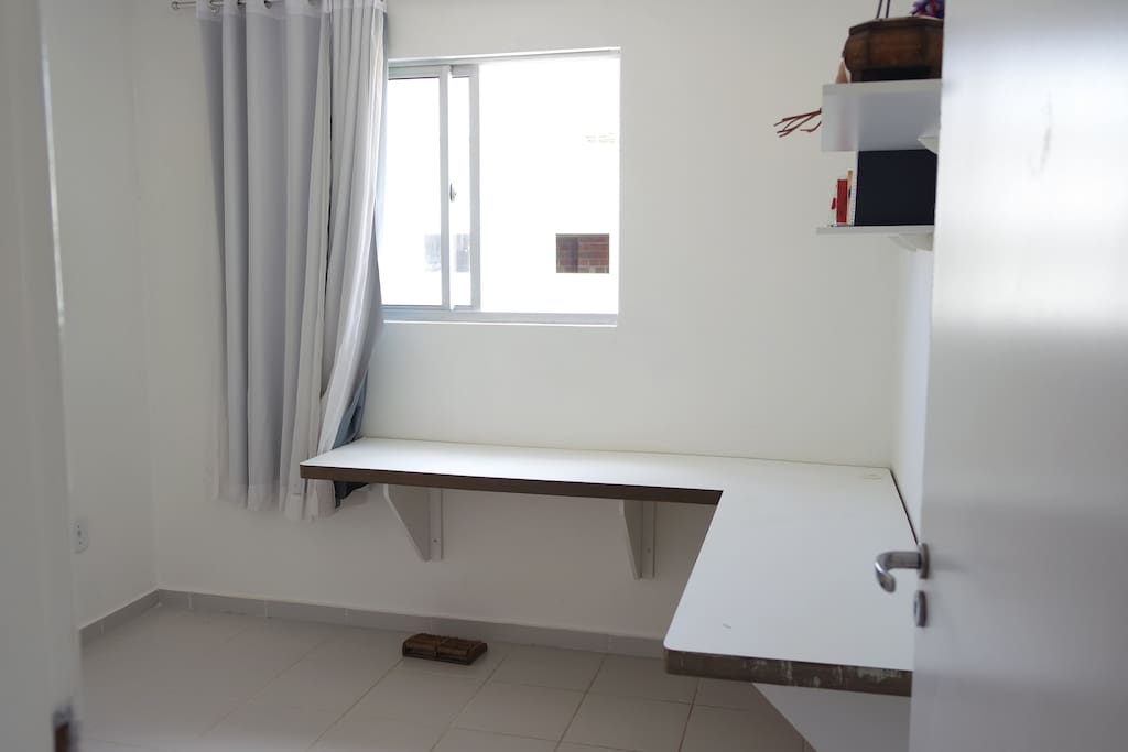 Quarto com mesa para trabalho ou acomodação de objetos pessoais.