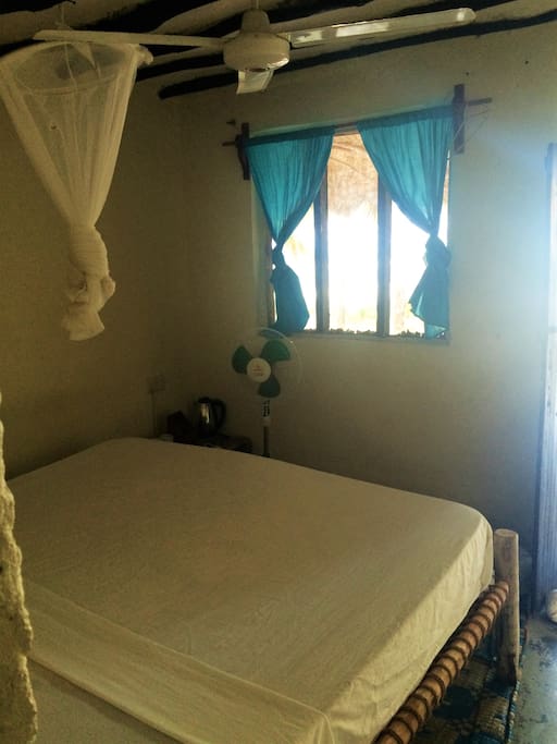 Large bed, fan, window with ocean view.