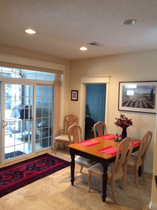 Six seat dining area with travertine stone tile and view out large sliding door to the covered patio and yard.