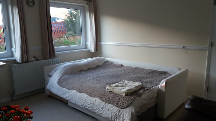 Large double bedroom containing a double bed settee, a settee and a TV. This room gets the morning sun.