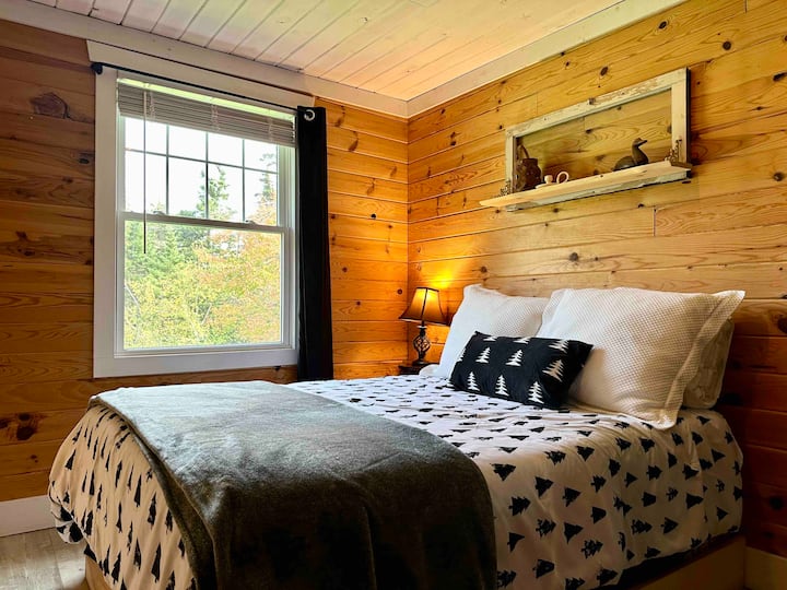The primary bedroom offers a comfy double bed with memory foam mattress topper, rustic knotty pine walls, antique dresser, and a large east facing window from which to watch the sunrise over the tree line. A tranquil mountaintop hideaway. 