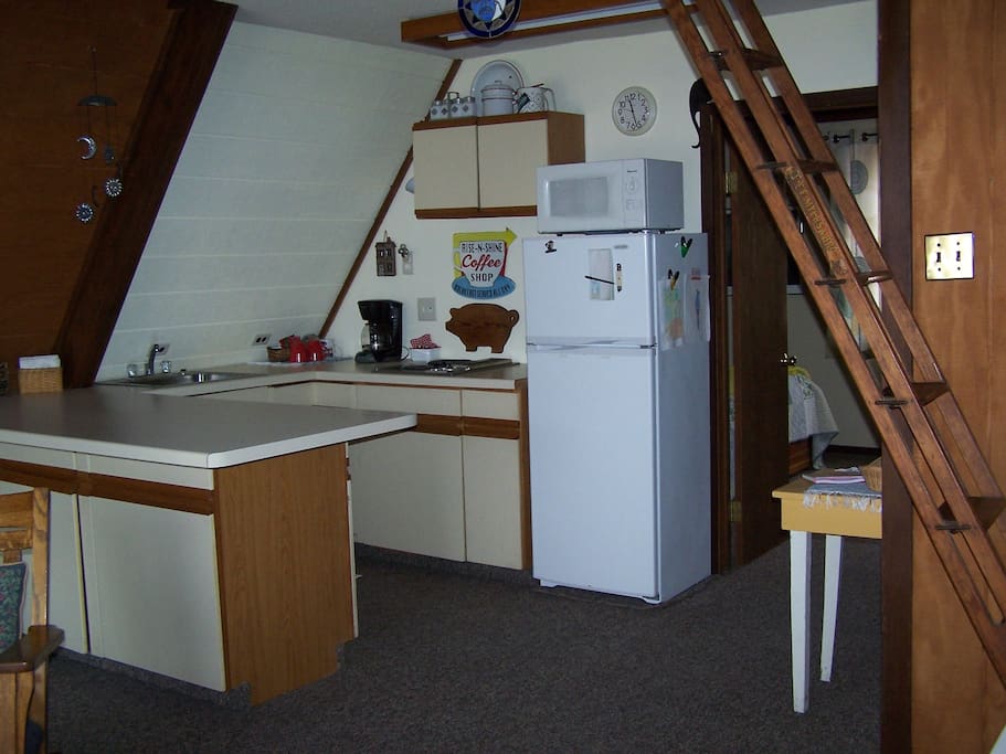 Kitchen with stove-top, microwave and coffee fixings.