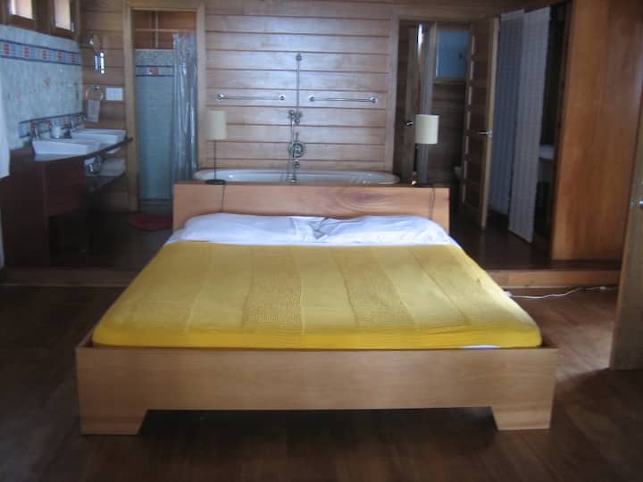 سرير بحجم كبير في غرفة النوم الرئيسية المفتوحة مع حمام مفتوح في الخلف
