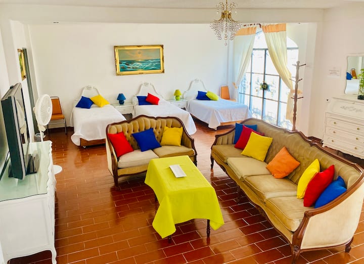 Habitación principal con 6 camas individuales y sala con TV.