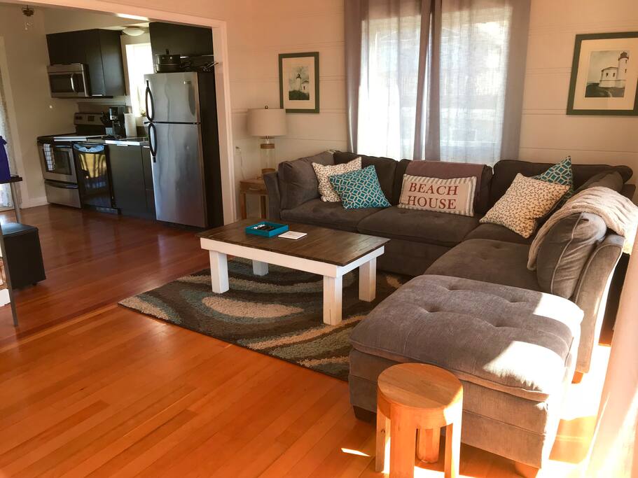 Open concept flow with 55 inch TV/DVD and a wall of floor to ceiling glass doors to look out on the shared porch with views of the ocean. Open Kitchen and Living room with a new comfortable couch.