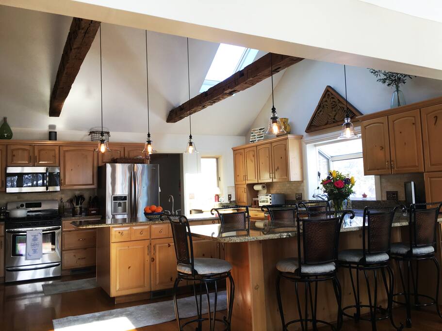 Gas stove and seating for six at the long counter. Barn wood beams on the high ceilings. Wine and beverage refrigerator attached to island.