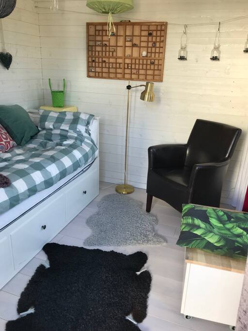 En säng en fåtölj med en bänk/bord med plats för bagage. Fårskinn på golvet som har golvvärme.