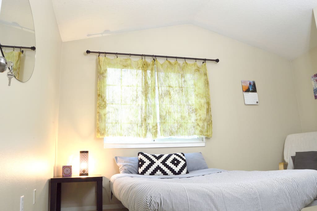 Bedside table with a bright modern lamp, and window facing towards the Willamette and West hills