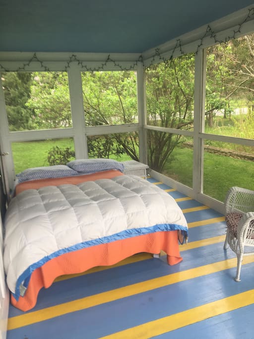 Queen bed with side table and comfy chair.