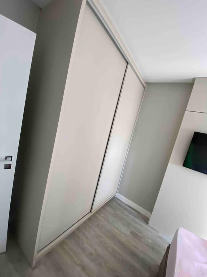 Dormitorio con armario, una cama doble y un televisor de 42 pulgadas, equipado con aire acondicionado.