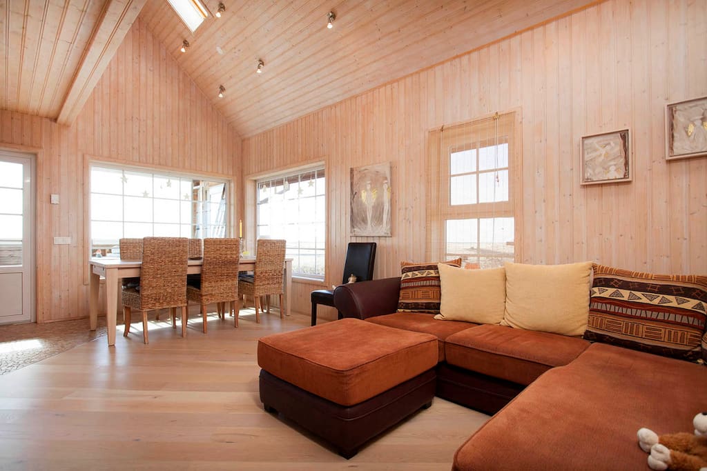The main room in the cabin. Large welcoming sofa and Tv, dining room and kitchen. Amazing view to pure Icelandic nature and the ocean