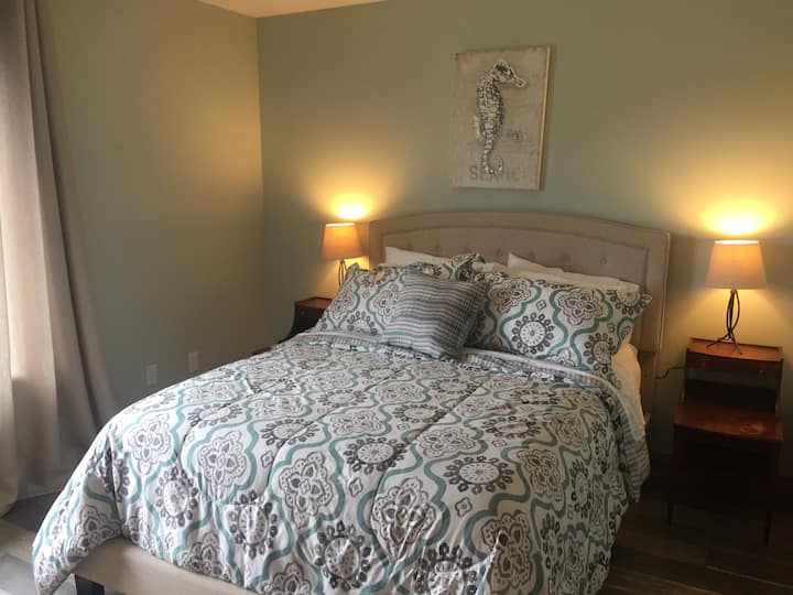 Upstairs bedroom with a pillow top memory foam queen bed, TV, and tower fan.