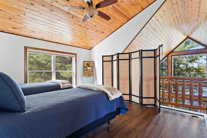The loft sleeping area with two Twin XL beds is open to the floor to ceiling living room windows with privacy screens provided. 