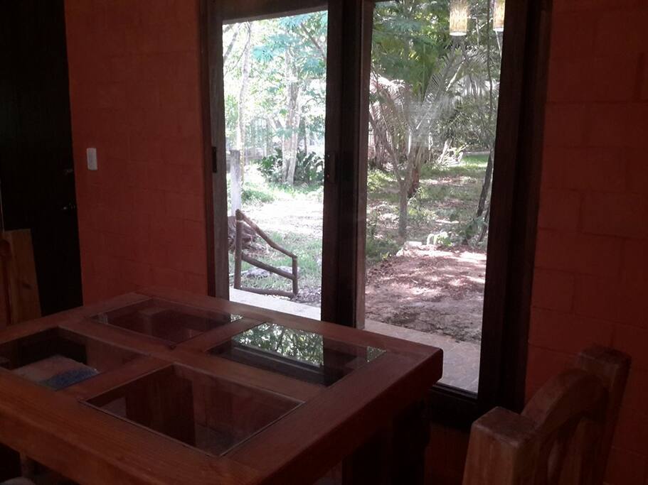 Hermosa vista al jardin, enmarcado por la pared de ladrillos de terracota que también por dentro le dan una atmosfera rustica y acogedora a su estancia. Mesa del comedor estilo rustico con madera gruesas y resistentes cubierta elegante que forman 4 paños de vidrio,