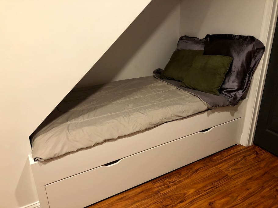 Trundle bed under the stairs in basement is a cozy sleeping area for two (2nd twin bed pulls out from under)