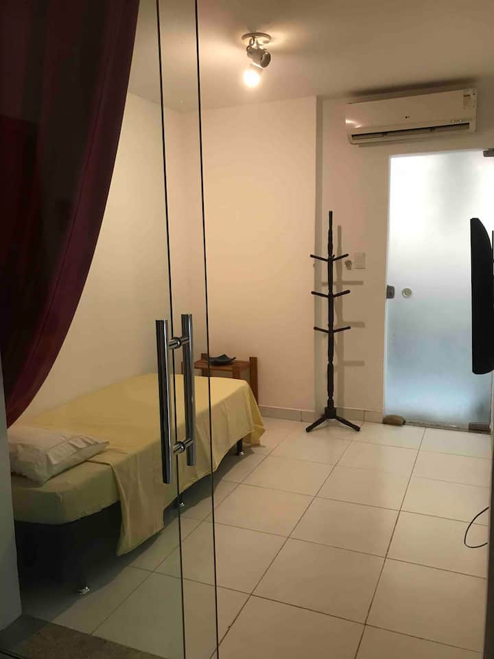 ห้องนอนพร้อมเตียงคู่ ม่าน เครื่องปรับอากาศ โทรทัศน์ และพื้นที่ทำงาน