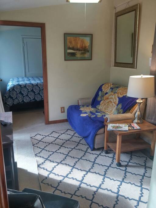Sitting room with love seat, end table and lamp. Bedroom is through the doorway.