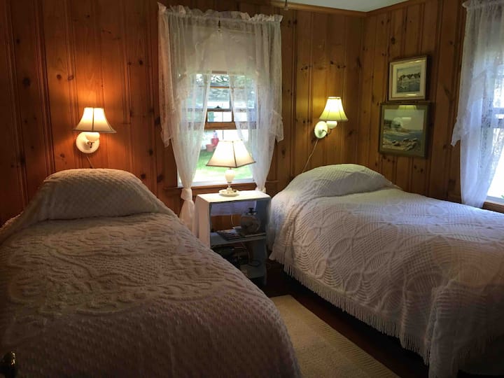 בחדר השינה יש שתי מיטות יחיד עם כריות מזרן, אורות קריאה מעל המיטה, מטען לטלפון 