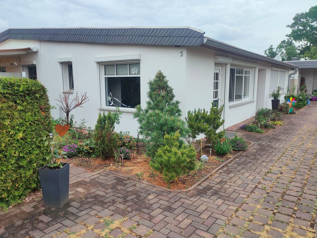 The exterior view of the property reveals a well-maintained garden with various plants and flowers lining the pathway. The building features large windows, allowing natural light to enter. A charming walkway made of paving stones leads to the entrance, enhancing accessibility.