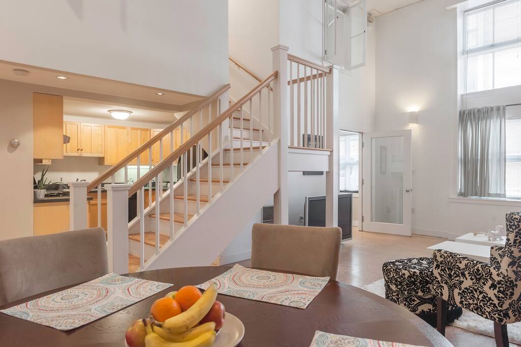 Airy and dramatic living space, stairs lead upstairs to the two bedrooms