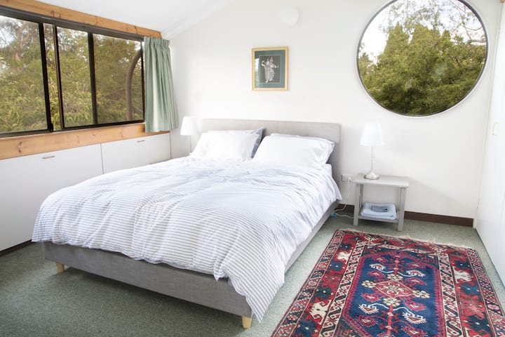 Спална соба со кружен прозорец со брачен кревет