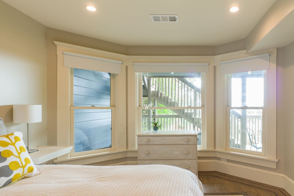 Sunny bedroom overlooks porch, with city views.