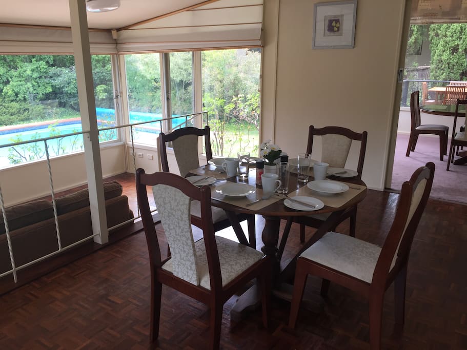 Small dining table off kitchen looking back over sun room and pool