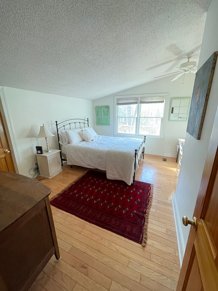 ห้องนอนใหญ่พร้อมเตียงขนาดควีนไซส์และที่นอนสีม่วง 