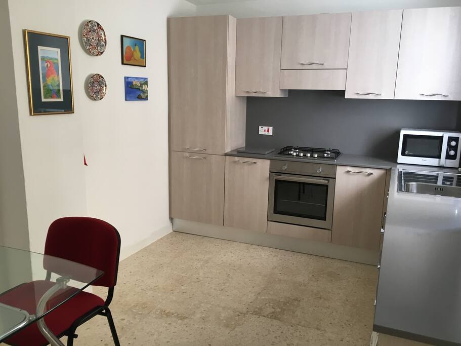 New kitchen with electric oven and gas hob and glad top table with two chairs. Wall mounted electric fan.