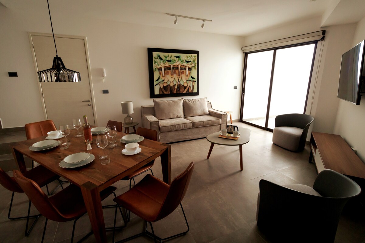 غرفة معيشة مريحة بسرير أريكة وأرائك فردية وتلفزيون ذكي وغرفة طعام حديثة