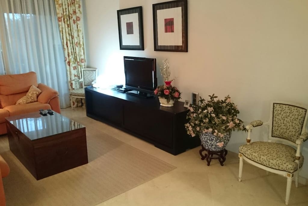 Cómodo salón- comedor, con mesa para 6 comensales, TV y terraza con vistas a la piscina