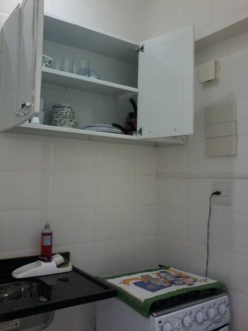 Cozinha equipada com fogão, pia, louças, panelas e talheres