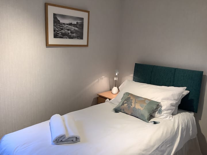 غرفة نوم واحدة مع طاولة بجانب السرير وتحت مخزن السرير