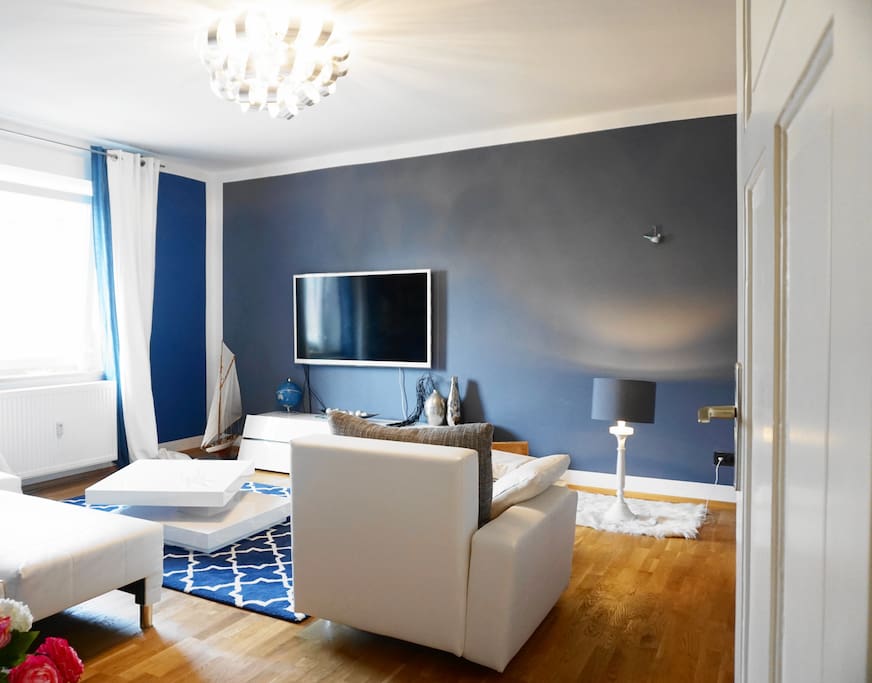 The living room offers a cozy couch and a comfy chair as well as a TV.