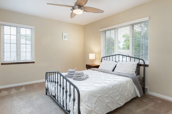 Une chambre lumineuse avec moquette moelleuse, lit accueillant et beaucoup de lumière naturelle filtrant à travers les stores.