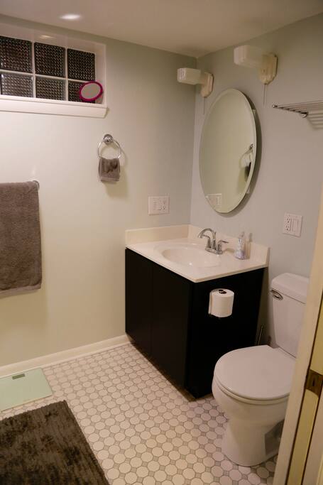 Spacious clean bathroom with step in shower, shampoo, conditioner, blow dryer and good lighting.