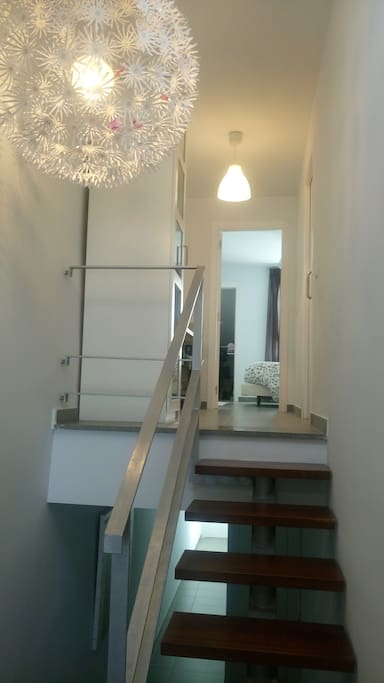 Escaleras hacia planta superior con dormitorio y baño