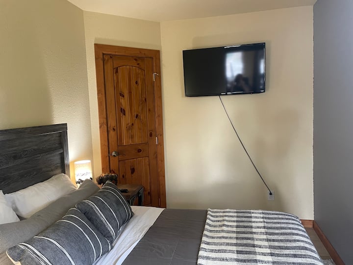 Full sized bed with closet area and mounted TV with cable.