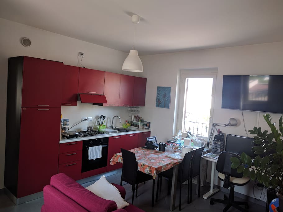 Soggiorno con cucina. A disposizione degli ospiti acqua, caffè, sale, aceto, olio e spezie, le stoviglie per mangiare e cucinare, bollitore, moka, piastra elettrica, forno, frigorifero e freezer. Per pernottamenti di lunga durata è disponibile anche la lavatrice, ferro da stiro