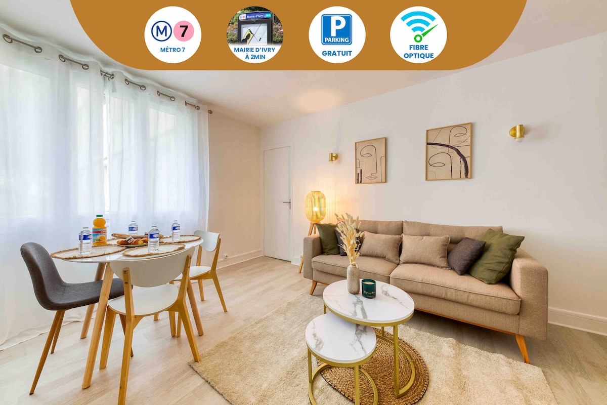A well-lit living area features a comfortable sofa and two round tables with seating for four. Decorative wall art and a modern floor lamp add subtle touches. Large windows provide natural light, creating a relaxed atmosphere for dining or leisure activities.
