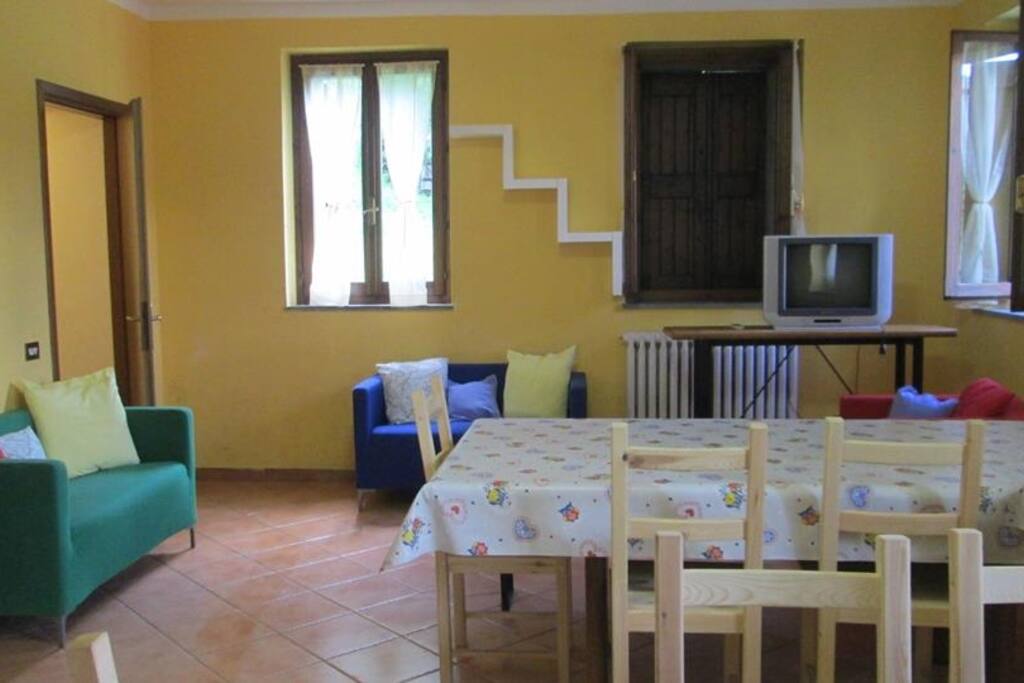Soggiorno con divani tavoli sedie e TV