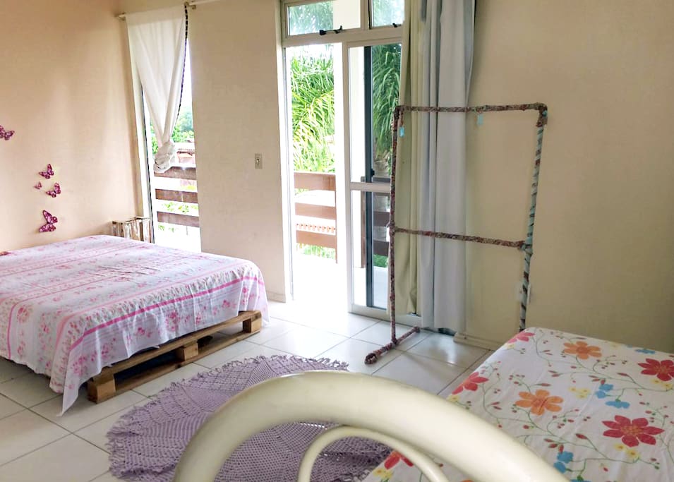 Suíte com varanda, cama de casal e cama de solteiro.