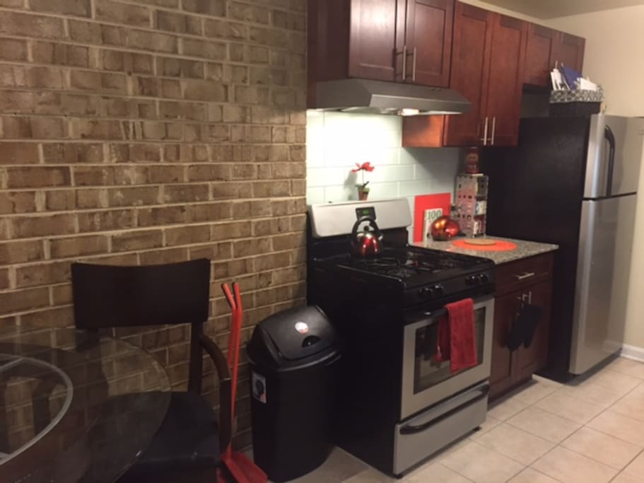 Exposed brick wall, granite counter tops, glass backsplash in kitchen.
