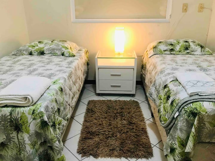 Ლამაზი და ფართო ოთახი 2 ერთადგილიანი საწოლით და დამხმარე საწოლით, რომელშიც არის სანათები, თეთრეული და აბაზანის პირსახოცები.