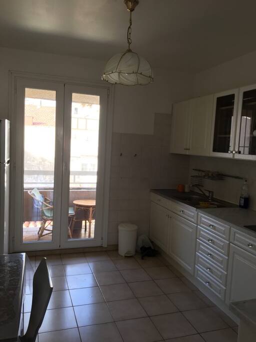 Une grande cuisine avec un petit balcon et une table (3chaises)