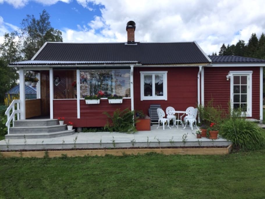 Trädäck med sjöutsikt. Trädäcket löper ända ner till sjön och avslutas med ett brett däck med utemöbler och grill.