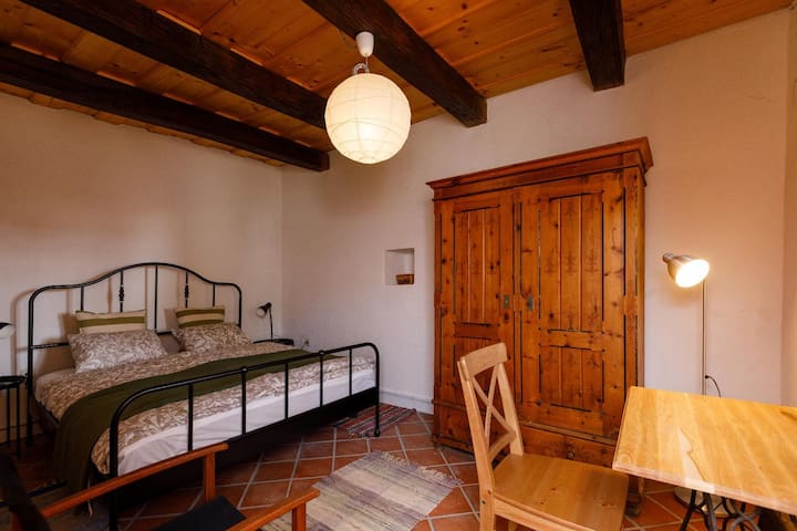 The downstairs bedroom. The table in front of the window is just big enough to put a laptop on it.
This bedroom opens from the stolen porch with a separate entrance. 
The bed is double, large, comfortable. Cool in the summer.