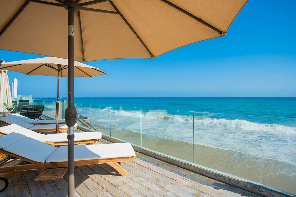 Situated right on the beach of the exclusive neighborhood in Malibu Colony. The property is one of the most sought-after rental properties available. Just steps below the deck is fresh sand and waves which lightly crash on to the beach shore. The deck area has multiple lounge chairs and umbrellas, perfect for relaxing and catching some of the California golden sun.