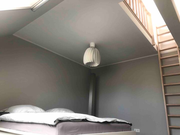 Spavaća soba u ambijentu maisonette. Stabilne drvene ljestve olakšava penjanje na mali „potkrovlje”. 